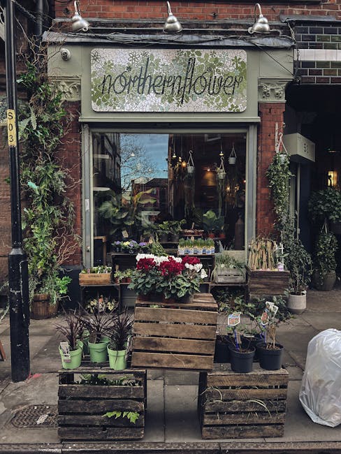 The storefront of northernflower, a florist located on a brick building façade with a painted sign above the window. In front of the shop, there are wooden crates and tables displaying potted plants,