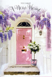 The scene unfolds at a cosy Stroud Green doorway, where the emotion of a first day in a new home is expressed through soft colour and delicate flowers. A pale pink door, painted with a slightly rustic, matte finish, sits at the centre of the composition, glowing gently as the late afternoon light brushes over its panels. Above, wisteria pours down from an unseen trellis in loose cascades of lavender and mauve, its tiny blossoms forming frothy, pendulous clusters that frame the entrance like a natural archway. The surrounding wall is whitewashed and lightly textured, while a nearby shutter in a coordinating pastel tone helps to weave the whole façade into a tranquil, storybook palette. On the doorstep rests a vintage-style metal bucket in soft grey, thoughtfully filled by a local florist with white and cream roses, their petals layered and generous, cushioned by subtle green foliage. A soft pink ribbon is tied at the base, its neat bow and flowing tails adding a hint of romance and refinement that mirrors the door's rosy hue. The light creates tender, painterly shadows around the flowers and along the stone step, suggesting a calm, sheltered corner just off the bustle of Stroud Green Road or close to leafy Finsbury Park. There is an unmistakable sense of hope and anticipation in this arrangement, ideal for a housewarming delivery to celebrate new keys, new rooms, and new routines. Every bloom seems to offer comfort and good fortune, turning an ordinary front step into a heartfelt welcome home.
