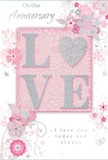 This anniversary card presents a tender, floral celebration of long-lasting love, as if it were a pastel bouquet designed for a quiet home just off Stroud Green Road. At its heart, the raised word "LOVE" stands out clearly from the surface, each letter dusted with fine, soft glitter that shimmers in shades of blush pink, pearlescent white, and delicate silver. The raised texture suggests a pleasing tactile experience, much like running your hands gently over fresh petals arranged by Flower Delivery Stroud Green. Around this central word, the card is adorned with an elegant frame of stylised blossoms and flowing foliage, all set against a soft pink background that feels calm and romantic. The flowers appear in subtle hues of blush, ivory, and the faintest lavender, their fine outlines and gentle shading echoing the careful planning that goes into arranging an anniversary bouquet for homes near Finsbury Park or the surrounding N4 streets. Silver-touched details highlight certain petals, leaves, and swirling lines, adding depth and a refined, celebratory sheen without becoming overpowering. Small flourishes, tiny petals, and curving stems give the impression of airiness, as if the design is drifting lightly across the card. A heartfelt anniversary message in graceful script completes the composition, its words quietly affirming commitment, gratitude, and shared history. Overall, the card feels like a softly fragrant, hand-drawn arrangement in paper form-a keepsake that gently mirrors the romance and intimacy of an anniversary bouquet delivered across Stroud Green.